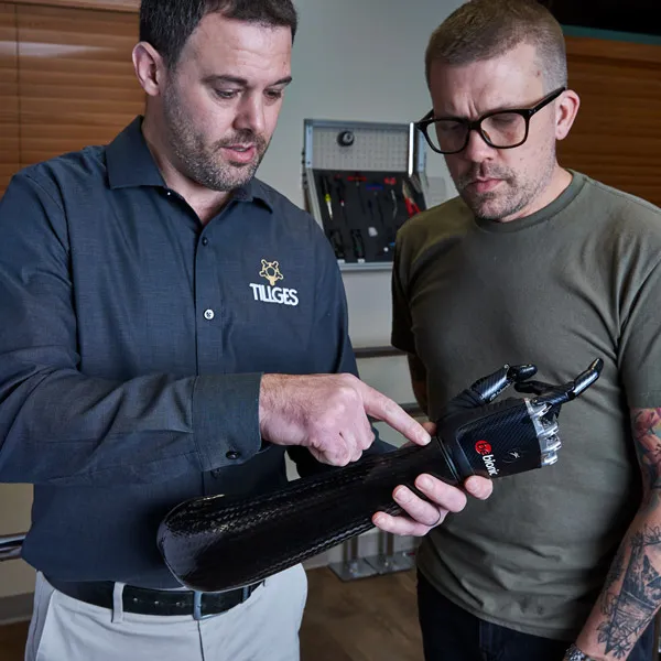 Two people looking at an upper extremity prosthetic